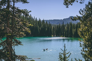 Two kayakers on a calm, pristine mountain lake