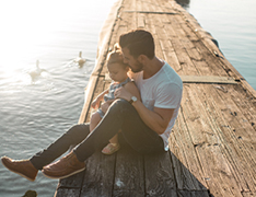 man sitting with daughter on pier