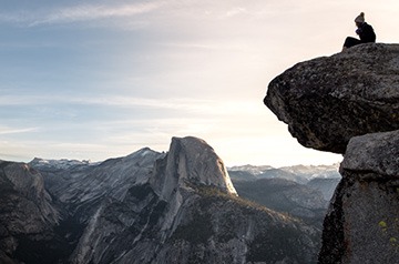 hiker on boulder viewing mountainous landscape