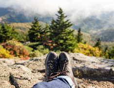 hiking boots in foreground, wooded landscape in background