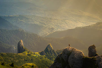 Hiker standing on rocks looking at mountain tops