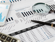 calculator, pen, and magnifying glass on balance sheets