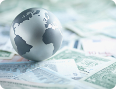 globe resting on stack of international currencies