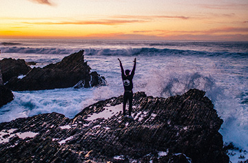 standing on rocks, waves crashing below