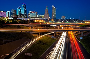 Headlights and taillights streaming on a highway toward a city.
