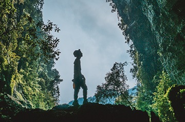 standing in cave, jungle behind