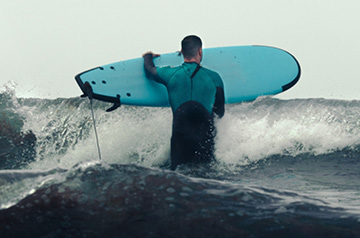 carrying surfboard into ocean