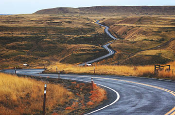 Looking down a winding road that runs through autumn-colored foothills