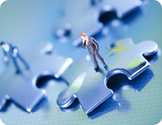 miniature toy businessmen atop puzzle pieces