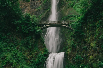 pedestrian bridge in front of waterfall