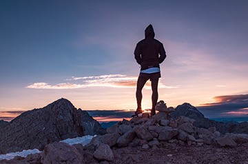 hiker watching sunset over mountains