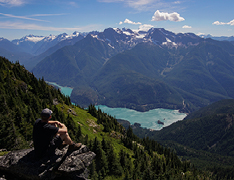 hiker overlooking mountain range, lake below