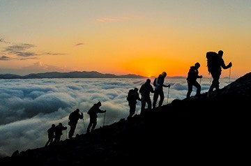 Group of hikers climbing a mountain trail at sunrise