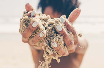 hands holding sand on beach