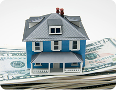 miniature toy house resting on a stack of US dollars