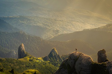 standing on rocks over wooded hills