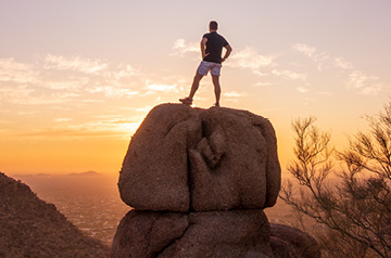 hiker standing on boulder overlooking landscape