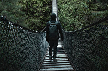 hiker walking across suspension bridge