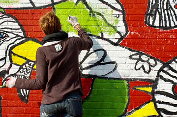 Person spray painting a brick wall