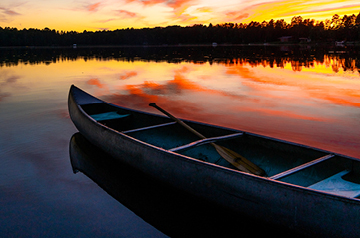 canoe on lake, sunset behind