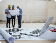 three people looking at blueprint on construction site