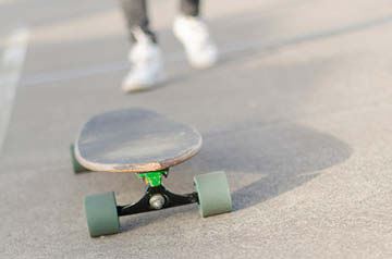 closeup of longboard, rider walking behind
