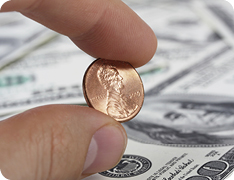 closeup of hand holding penny with index finger and thumb