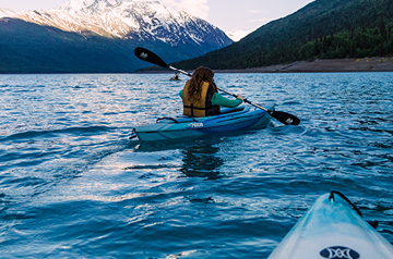 kayaking in open water, cliffs behind