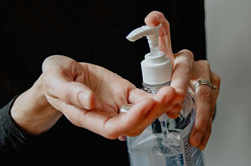 Two hands applying hand sanitizer