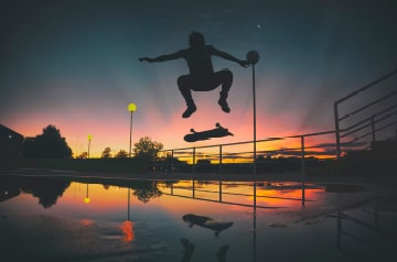 silhouette of skateboarder doing trick at sunset