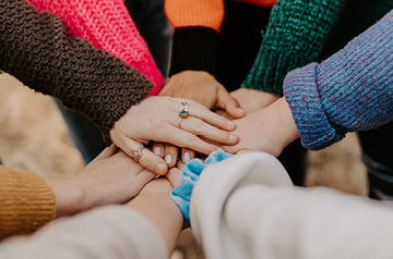 group of friends with all hands in the middle
