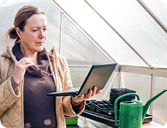 woman holding laptop in nursery greenhouse