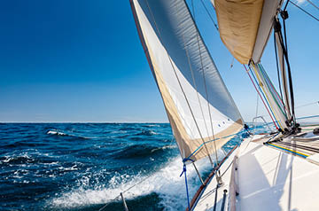 View of the deck of a small sailboat racing through the water.