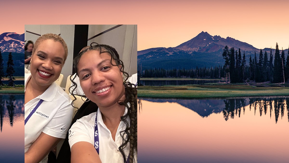 Women posing at the 2024 NABA conference, over a background with a mountain reflected in water