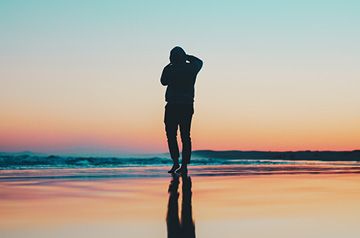 silhouette of person standing on beach at sunset