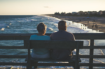 couple sitting on bench on pier