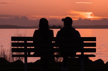 silhouette of couple on bench at sunset