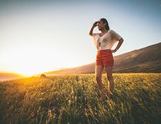 woman standing in field at sunset