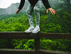 person balancing on forest path guardrail