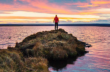 standing on ocean shore at sunset