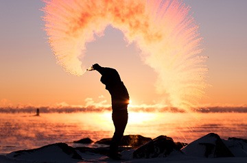 Silhouette of a person standing on rocks near the ocean