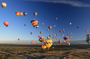 Fleet of hot air balloons floating in blue sky