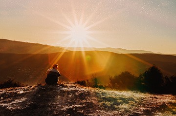 hiker watching sunset over hills