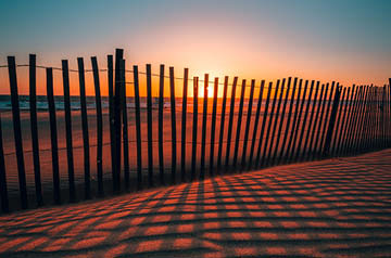 fence on beach at sunset