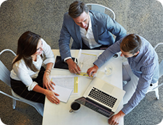 businesspeople sitting around one laptop