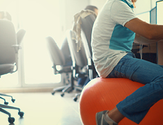 person sitting on exercise ball in office space
