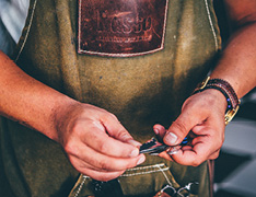 person handling tools and wearing apron