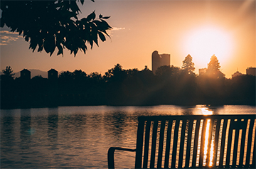 A park bench, a sunset, and a lake