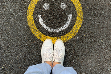 Two feet standing on the pavement by a happy face