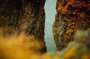 abstract photo of narrow space between cliffs, ocean behind